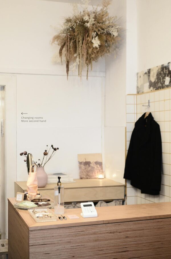 Interior of contemporary light clothes store or atelier studio with dry decorative plants on wooden counters