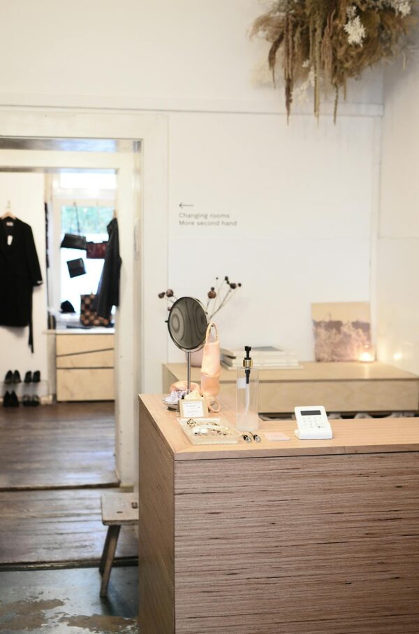 Stylish interior design of modern light clothes store or atelier studio with wooden counter and changing room